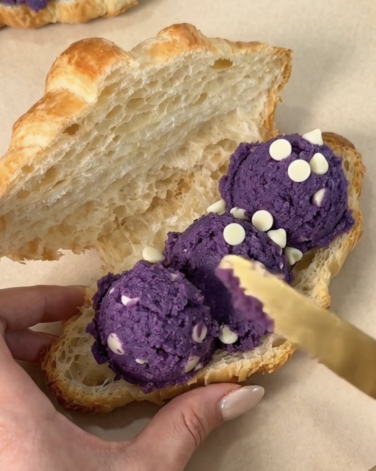 UBE NOLIA® purppura ube (purple yam) valkosuklaacookietaikinan lusikoiminen viipaloituun voicroissanttiin ube crookien valmistamiseksi