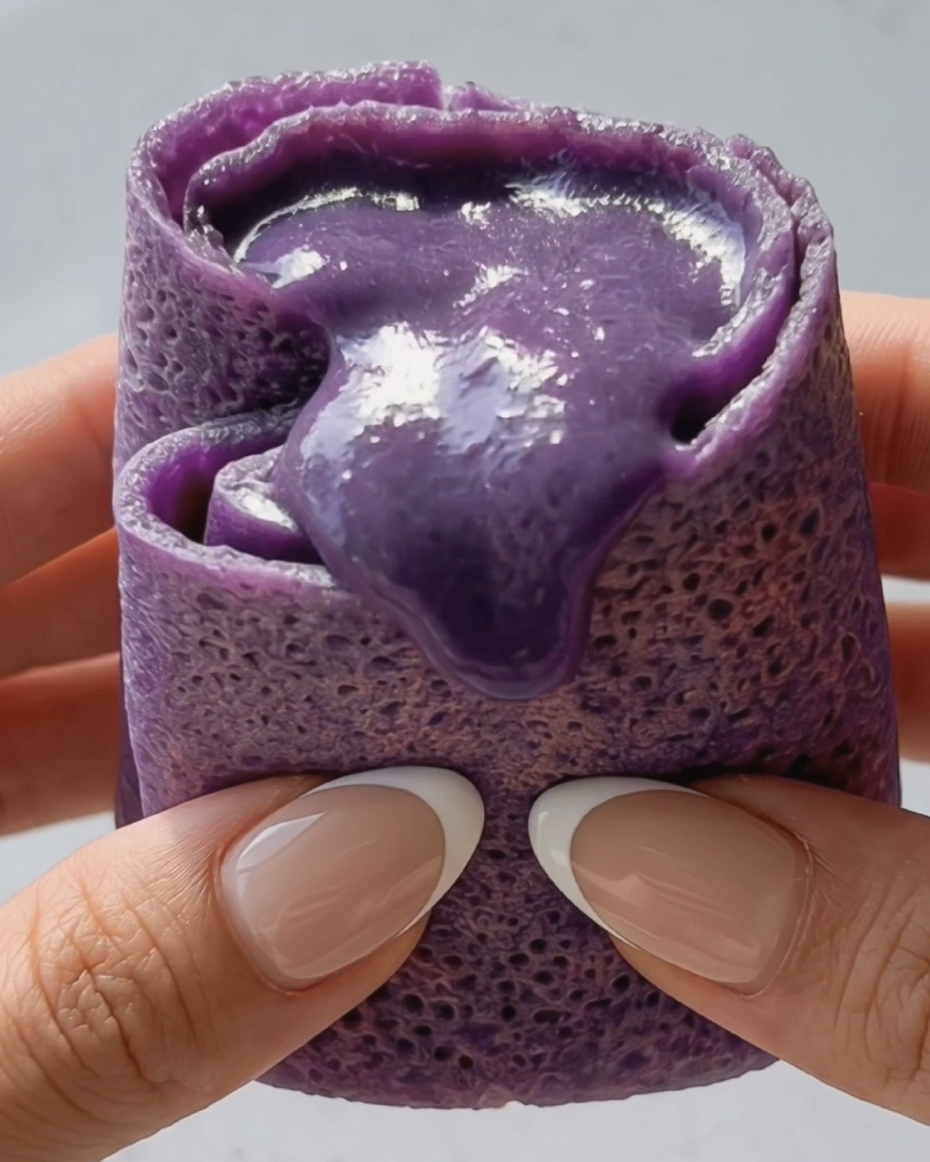 Ube dadar gulung -lettu halkaistu paljastaen silkkisen kermaisen violetin ube halaya -täytteen sisällä