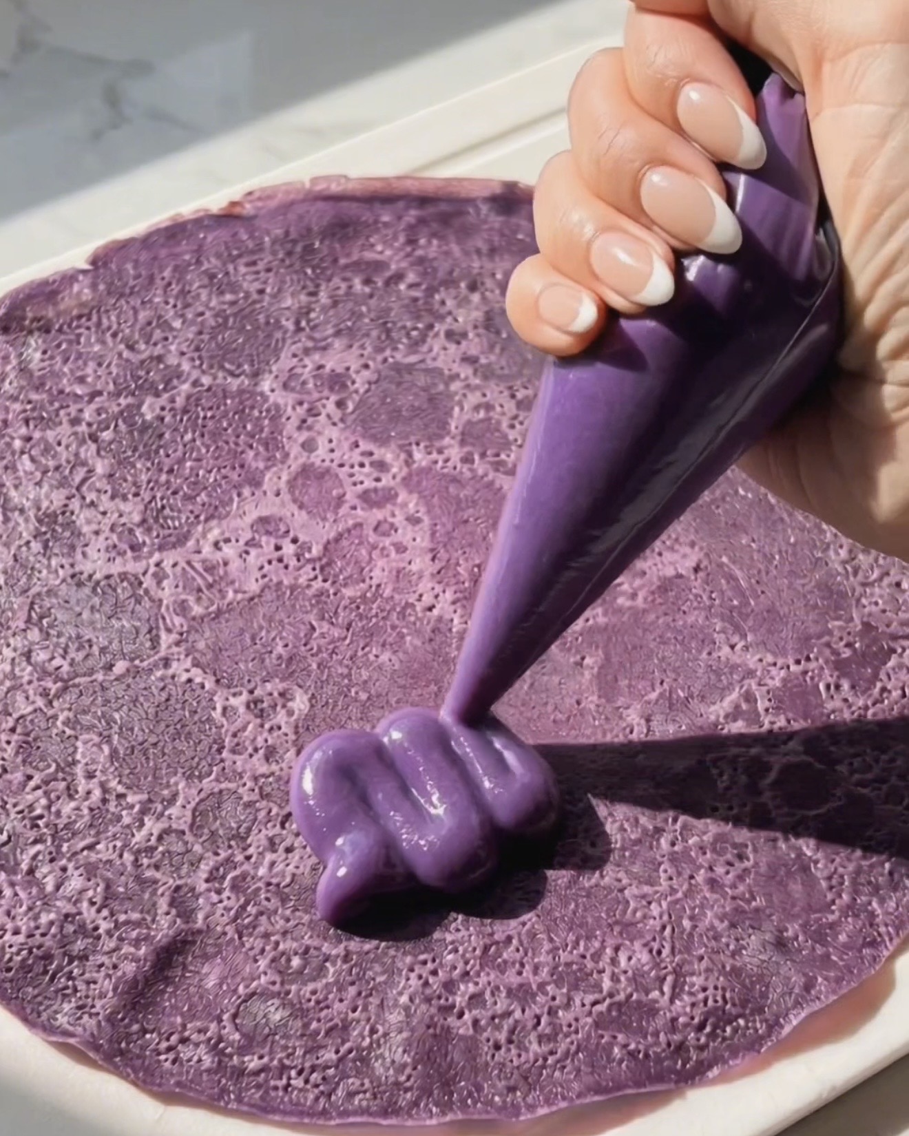 Ube halaya -täytteen pursottaminen violetin ube-letun päälle dadar gulungin kokoamiseksi