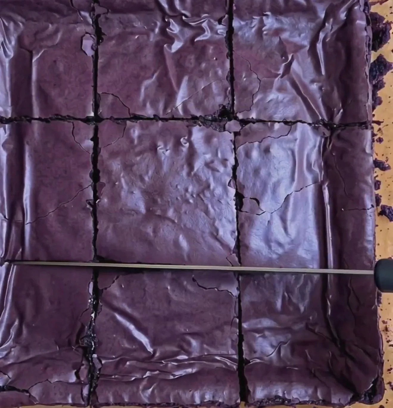 Paistetut tahmeat ube-browniet, joissa on kiiltävä syvän purppura ryppyinen pinta, leikattuna 9 neliöön Ube Nolia -jauheen kanssa
