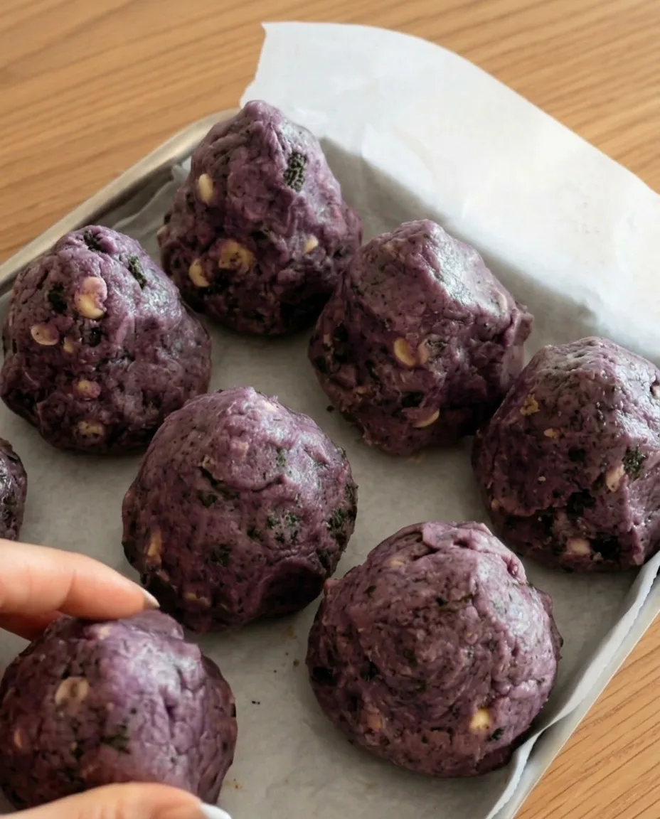 Purppuranväriset ube Oreo -keksitaikinapallot leivinpaperilla valmiina pakastukseen New York -tyylisiä paksuja keksejä varten