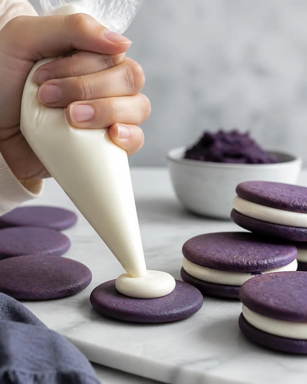 Ube Oreo -keksien täyttäminen – valkosuklaaganachen pursottaminen purppuroille ube-vohveleille | Ube Nolia