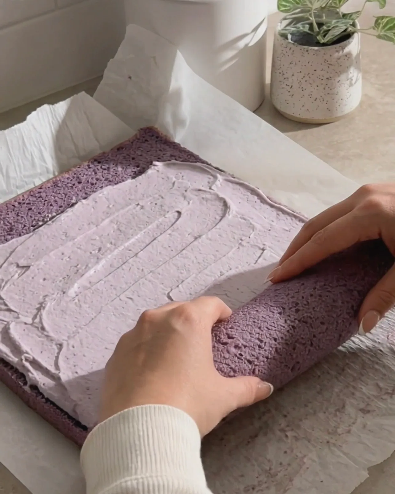 Ube-kermavaahdon levittäminen purppuralle sifonikakulle ja sen rullaaminen Ube Nolia -brändiltä